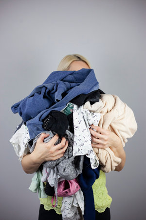 woman holds a lot of crumpled clothes in her hands, copy-pasteの写真素材