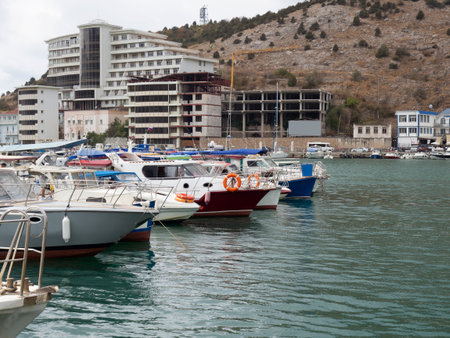 Pleasure yachts on the Black Sea coast with a mountain and a building in the backgroundの写真素材