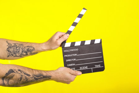 director's clapper. hands with a boardÑlapper on a yellow background. cinema conceptの写真素材