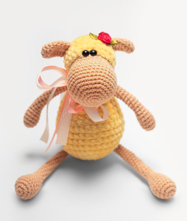 Cute handmade toy. knitted little animal. yellow sheep. on a gray background. Crochet stuffed animals.の写真素材