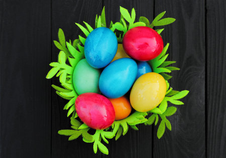 Basket with colored easter eggs. Easter holiday. on wooden background