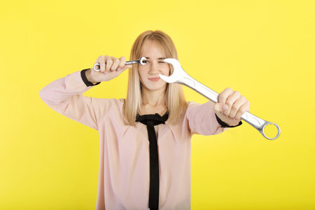 girl holding wrenches in her hands. on a yellow backgroundの写真素材