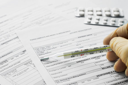 Thermometer in man hand on patient registration formの写真素材
