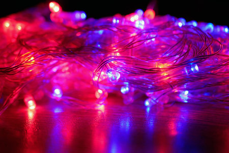 Illuminated christmas garland with red and blue lamps on black background. Focus on the middle ground.の写真素材