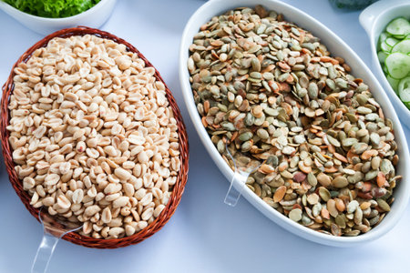 Earth nuts and Pumpkin seeds in bowls on a white table 
