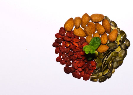 Mix of almonds, goji seeds, pumpkin seeds and fresh mint leaves in the middleの写真素材