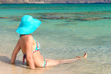 Beautiful young woman in bikini with sunhat, relaxing on the sunny beach. Relaxing conceptの写真素材
