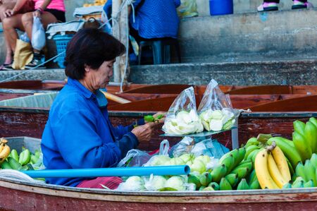 Ratchaburi, Thailand - May 24, 2014: Thai locals sell food and souvenirs at famous Damnoen Saduak floating market on  May 24, 2014 in Thailand, in the old traditional way of selling from small boats.のeditorial素材