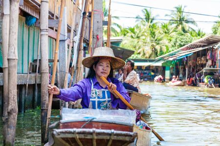 Ratchaburi, Thailand - May 24, 2014: Thai locals sell food and souvenirs at famous Damnoen Saduak floating market on  May 24, 2014 in Thailand, in the old traditional way of selling from small boats.のeditorial素材