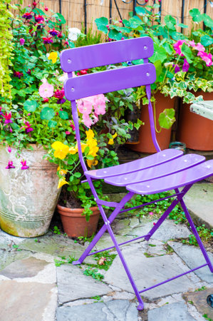 View of purple chair surrounded by various colorful flowersの写真素材