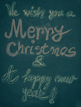 We wish you a Merry Christmas and a happy new year, hand writing with chalk on blackboard, vintage conceptの写真素材