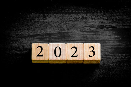 Year 2023. Wooden small cubes with numbers isolated on black background with copy space available. New Year Concept image.の写真素材