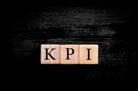 Acronym KPI - key performance indicator. Wooden small cubes with letters isolated on black background with copy space available. Business Concept image.の写真素材