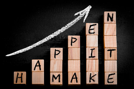 Message MAKE IT HAPPEN  on ascending arrow above bar graph of Wooden small cubes isolated on black background. Chalk drawing on blackboard. Business Concept image.の写真素材