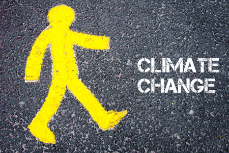 Yellow pedestrian figure on the road walking towards CLIMATE CHANGE. Conceptual image with Text message over asphalt background.の写真素材