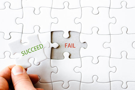 Hand with missing jigsaw puzzle piece. Word SUCCEED covering  text FAIL. Business concept image for completing the final puzzle piece.の写真素材