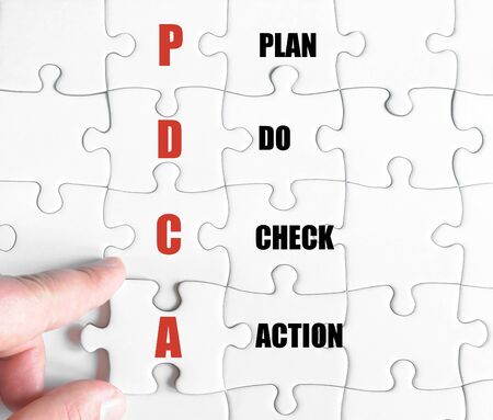 Hand of a business man completing the puzzle with the last missing piece.Concept image of Business Acronym PDCA as Plan Do Check Actionの写真素材