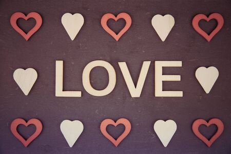Word LOVE created of wood letters over vintage chalkboard,  with red heart shape symbols, retro filter applied, conceptual imageの写真素材