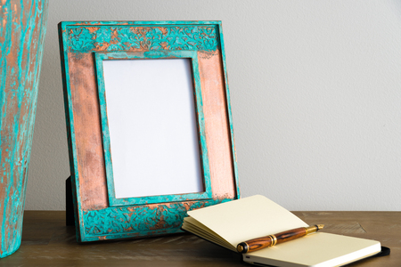 Vintage photo frame on wooden table over white wall background with empty white canvas, copy space availableの写真素材