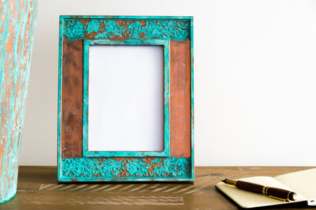 Vintage photo frame on wooden table over white wall background with empty white canvas, copy space...