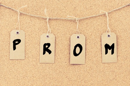 Vintage grunge tags with letters on rope string, word PROM over cork board texture background, filter applied, available copy space.の写真素材