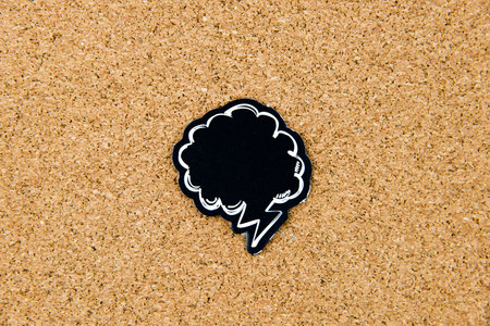 Empty black speech bubble over cork board background, copy space available