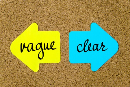 Message Vague versus Clear on yellow and blue paper notes as opposite arrows pinned on cork board with thumbtacks. Choice conceptual imageの写真素材