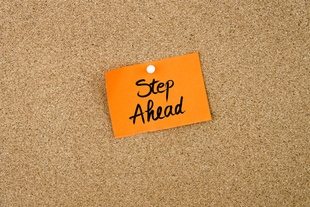 Step Ahead written on orange paper note pinned on cork board with white thumbtacks, copy space availableの写真素材