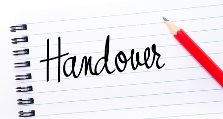 Handover written on notebook page with red pencil on the rightの写真素材