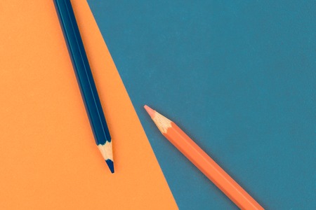 Orange and Dark Blue coloured pencils and paper, abstract contrast conceptual imageの写真素材