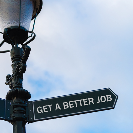 Street lighting pole with conceptual message GET A BETTER JOB on directional arrow over blue cloudy background.の写真素材