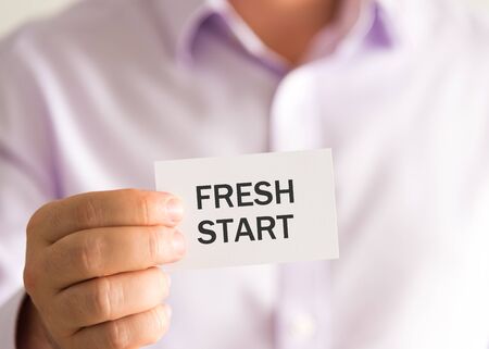 Closeup on businessman holding a card with text FRESH START, business concept image with soft focus backgroundの写真素材