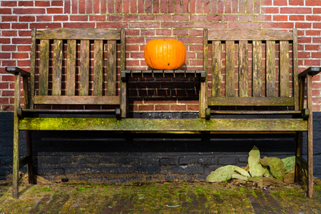 Pumpkin standing on vintage wooden table and chairs against brick wall, Halloween conceptの写真素材