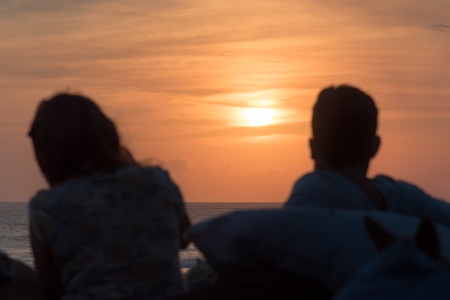 Silhouette of unrecognisable man and woman at seaside on sunsetの写真素材