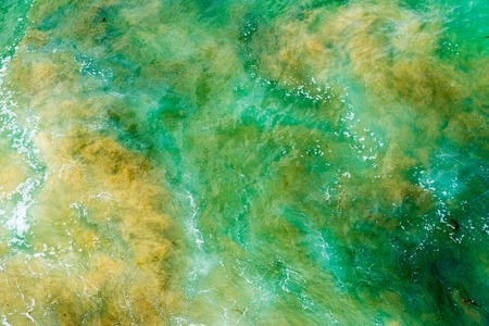 Top aerial view of blue green waves crashing on rocky Australian coastline. Summer seascape with ocean waves. Travel concept backgroundの写真素材