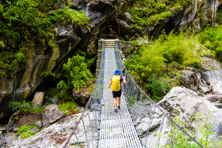 Annapurna Conservation Area, Nepal - July 19, 2018 : Woman backpacker on trekking path crossing a suspended bridge in Annapurna Conservation Area, a hotspot destination for mountaineers in Nepalのeditorial素材