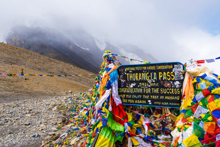 Annapurna Conservation Area, Nepal - July 28, 2018 : Information sign and prayer flags on Thorang-la pass, Annapurna Circuit, Annapurna Conservation Area, the largest protected area of Nepalのeditorial素材