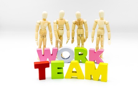 Wooden figures posing as business men behind the words TEAM and WORK, isolated on white. Team, unity and collaboration conceptの写真素材