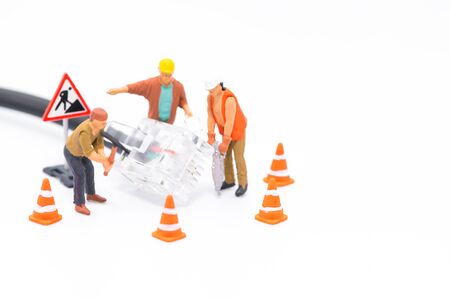 Macro shot on miniature figures as technicians working on the internet web network repair cable socket, isolated on white background. Information technology IT and business conceptの写真素材