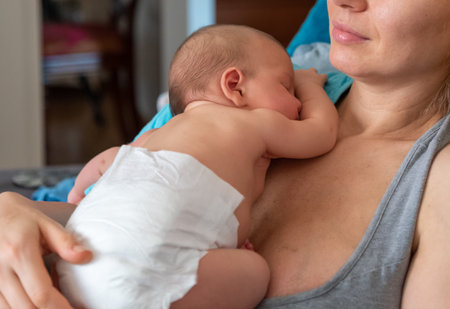 Cute 2 months little baby boy sleeping in his mothers arms