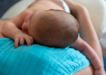 Cute 2 months little baby boy sleeping in his mothers arms