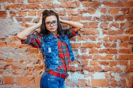 Beautiful young woman stands near the old brick wall. Youth stylの写真素材