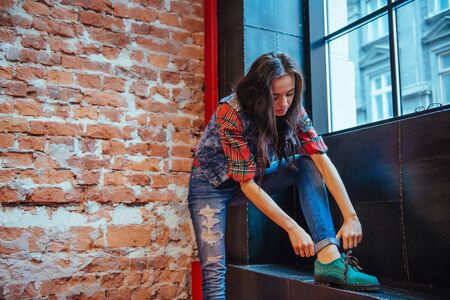 Beautiful young woman stands near the old brick wall. Youth stylの写真素材