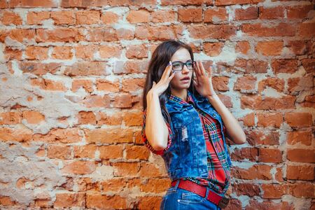 Beautiful young woman stands near the old brick wall. Youth stylの写真素材