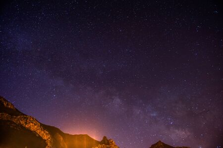 The starry sky above rocky mountains.の写真素材