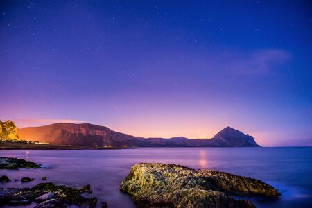The starry sky above rocky mountains.の写真素材
