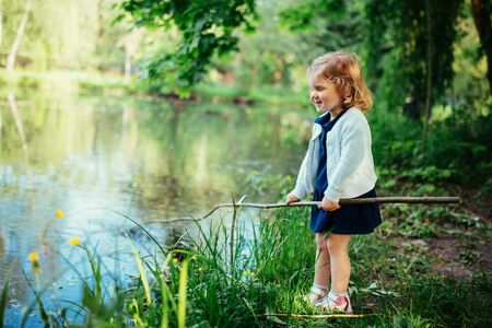 Cute little blonde girl is against the background of water and gの写真素材