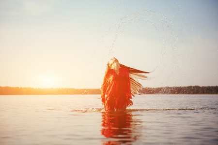 woman on water background at sunsetの写真素材