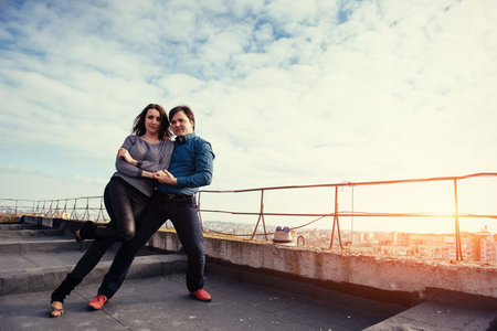 young couple dancing on the roof of a tall building
