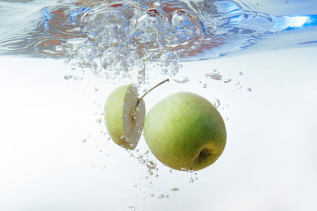 Green apple under water with a trail of transparent bubblesの写真素材